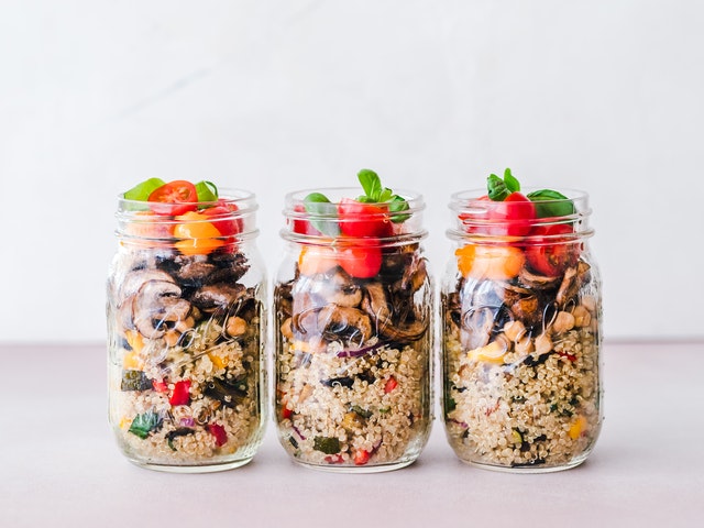 Three clear glass mason jars filled with healthy food.