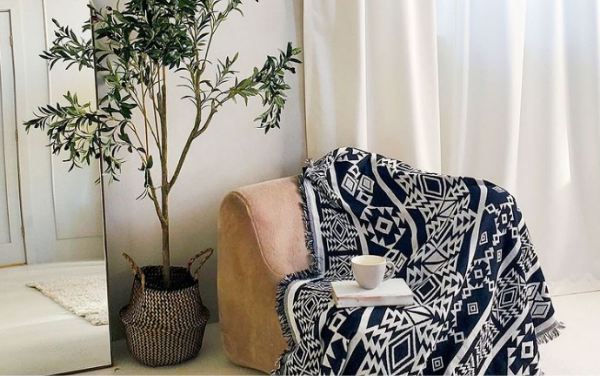Oversized throw blanket draped across chair with book and coffee placed on top.