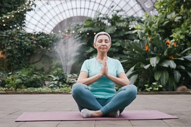 Woman sitting cross-legged on yoga mat in a zen state.