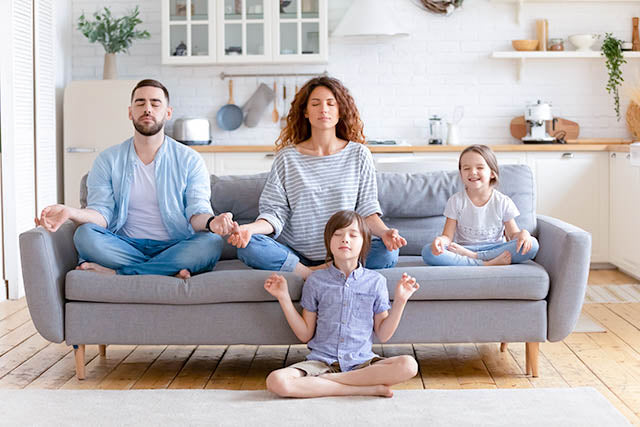 Family of four meditating on couch in living room