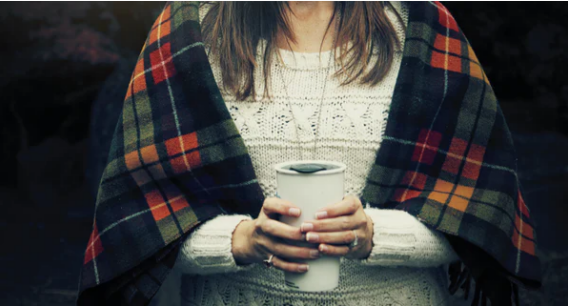 Woman wrapped in blanket holding coffee
