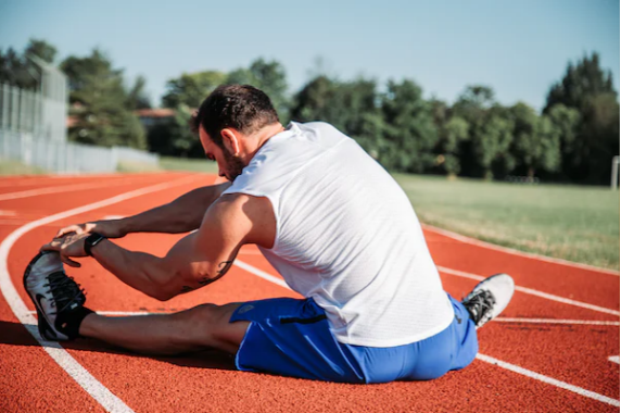 man stretching on outdoor track