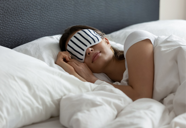 Woman sleeping while wearing a black and white striped sleep mask.
