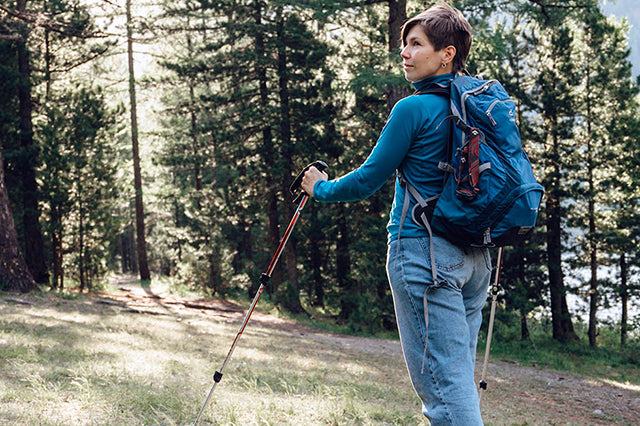 Woman hiking in the woods with walking sticks 